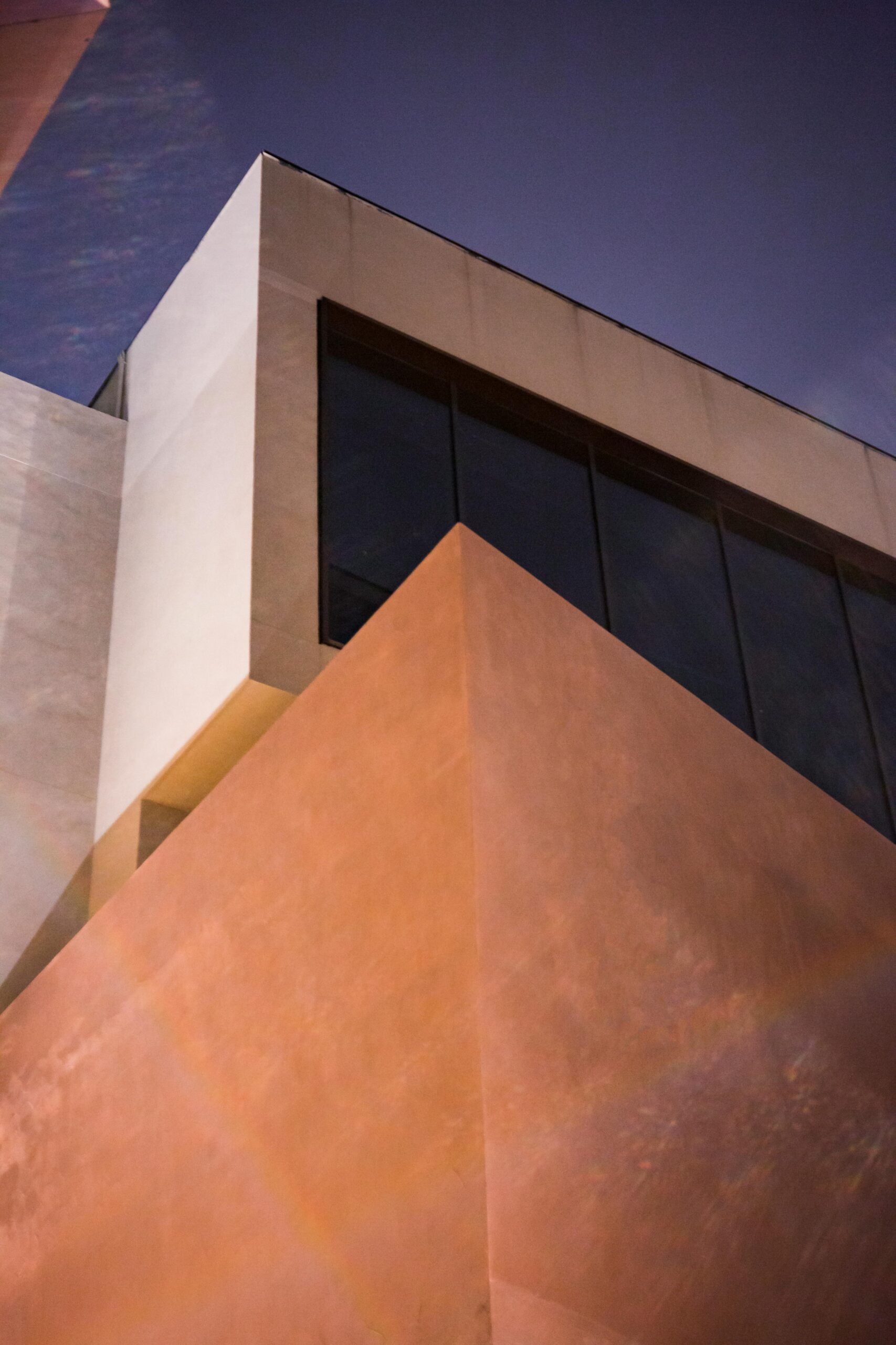 Low-angle shot of a modern building featuring geometric shapes and glass windows.